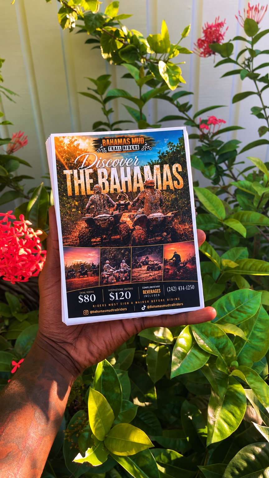 A hand holding the original Bahamas Mud Trail Riders printed flyers in a sunlit garden