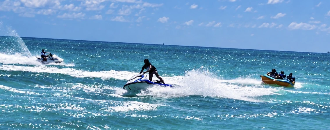 Jet skis and an inflatable crossing sunlit water.